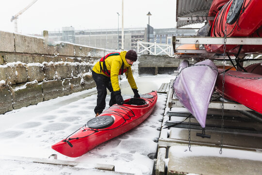 Adventurer Preparing Kayak on Frozen Ocean Shore in Winter