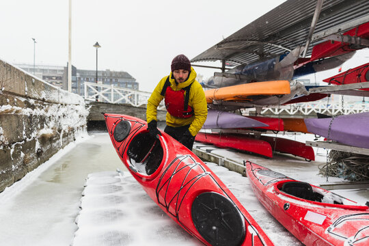 Adventurer Preparing Kayak on Frozen Ocean Shore in Winter