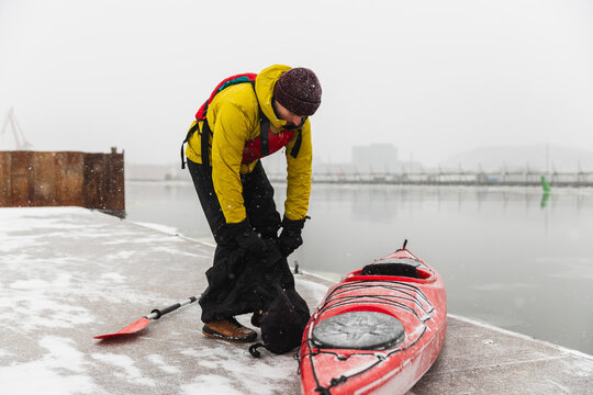 Kayaker Preparing Gear on a Snowy Urban Waterfront