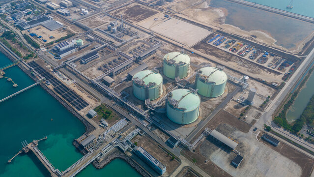 Massive LNG storage tank facility at an industrial coastal terminal. Global natural gas energy logistics, liquid fuel cargo container supply chain, and petroleum distribution trade concept.