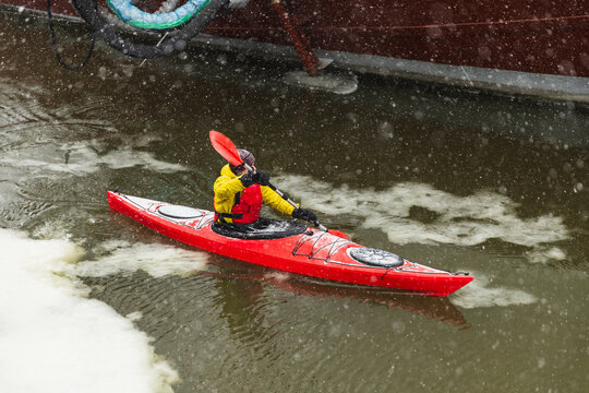 Red Kayak Navigating Through Icy Sea Water During Snowfall