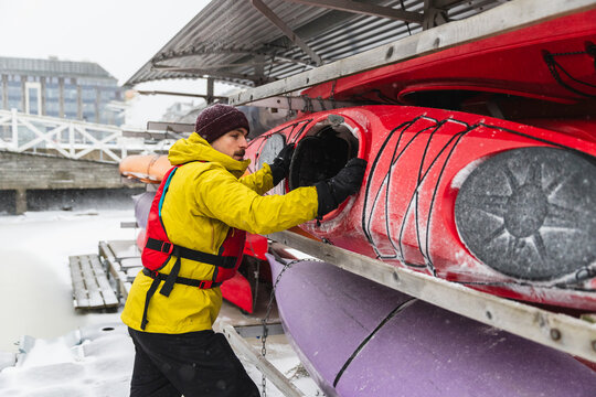Adventurer Preparing Kayak on Frozen Ocean Shore in Winter