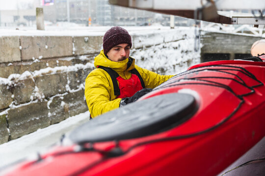 Adventurer Preparing Kayak on Frozen Ocean Shore in Winter