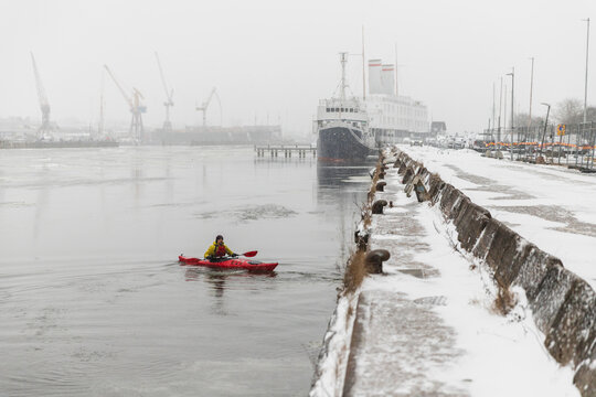 Red Kayak Navigating Through Icy Sea Water During Snowfall