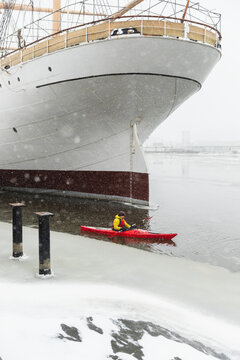 Red Kayak Passing the Bow of a Large White Ship in Winter