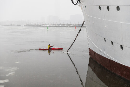 Small Red Kayak Paddling Near Massive Ship Anchor Chain