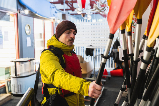 Adventurer Choosing Paddle in Gear Shop Before Winter Kayaking