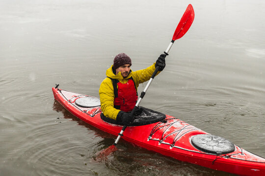 Side View of Kayaker Paddling Red Boat in Icy Urban Bay