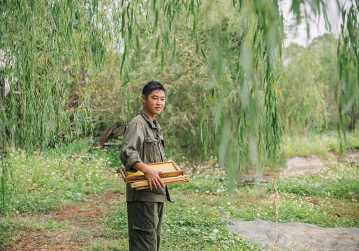 Chinese man inspects his beehives outdoors