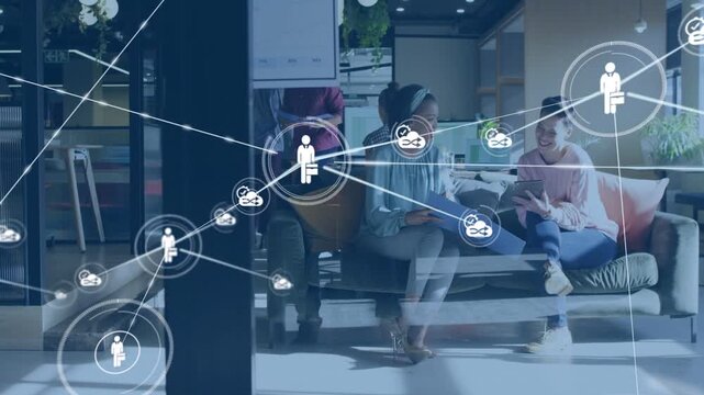 Chatting two women in blue-top, pink-sweater tapping tablet on office sofa, node appearing, growing