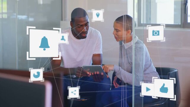 Team pointing and tapping tablet in glass pod causing floating social icons showing business tools