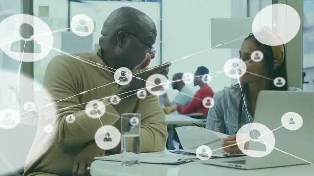 Senior mentor pointing at papers mentee writing causing network overlay to fill frame for education