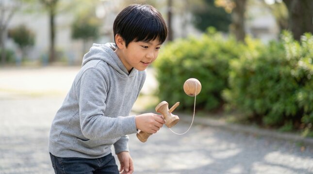 Japanese child playing kendama in park during sunny day  