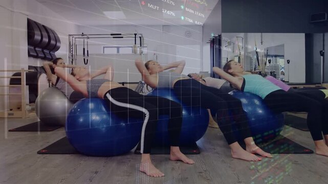 On cue four women performing core curls on balls in fitness studio, mid routine charts overlaying