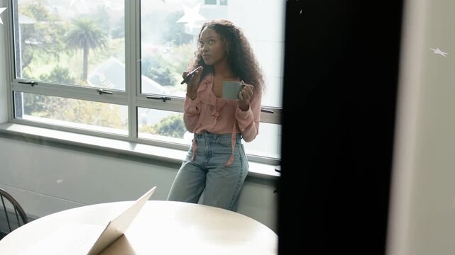 Camera panning revealing woman on sill holding mic, mug, recording with laptop, stars crossing face