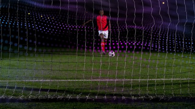 Male soccer player approaching ball, taking penalty kick aiming to score and rippling net with LED