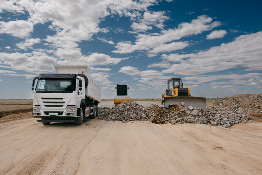 Dump Truck and Bulldozer Working on Gravel Road Construction