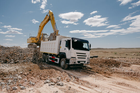 Excavator Loading Rocks Into Dump Truck at Quarry