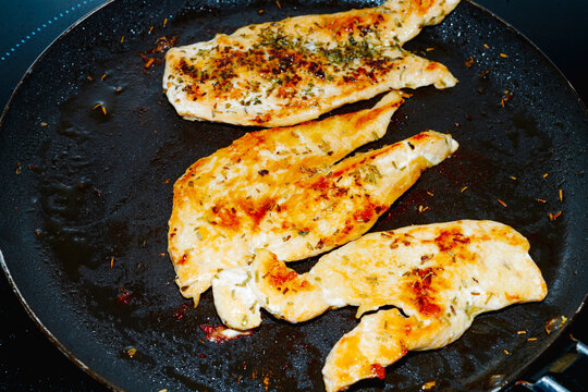 frying pan with several chicken breast fillets