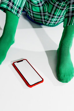 a blank smartphone screen rests between the feet of a man