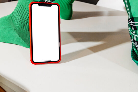 a smartphone framed by the legs of a man on a table