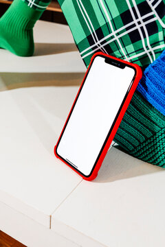 a blank phone leans against the leg of a man