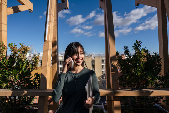 Woman talking on phone in urban garden setting
