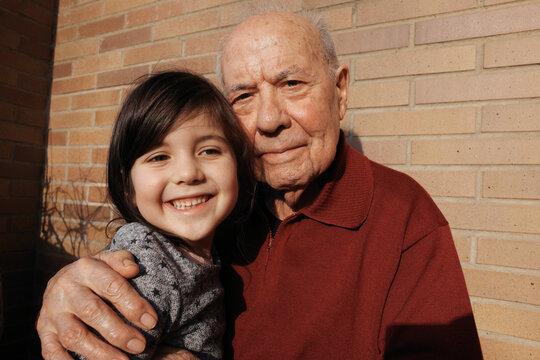 A Young Girl Laughs While Holding Her Grandfather Close