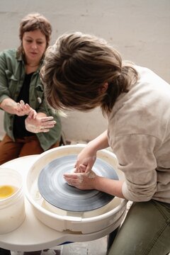 Student shaping clay on pottery wheel