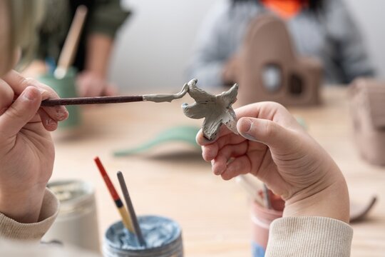 Child Painting Clay Sculpture