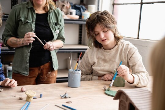 Student Painting Clay Sculpture in Art Class