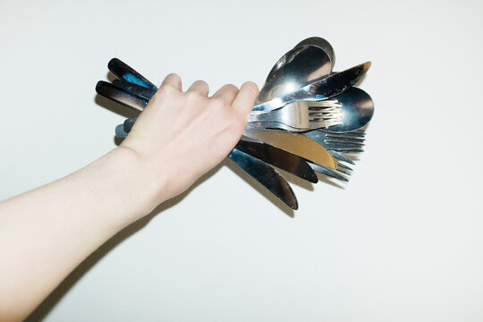 Hand holding punch of shiny silver eating cutlery with flashlight