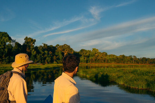Men ecotourism in Amazon lake at golden hour