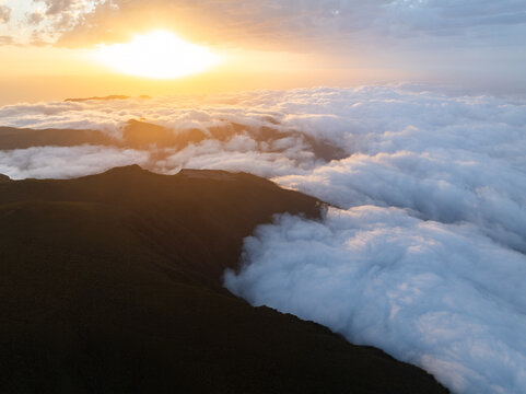 Aerial view of the Bica da Cana mountain ridge rising above a dense sea of clouds during a golden sunset Ponta do Sol, Madeira, Portugal.