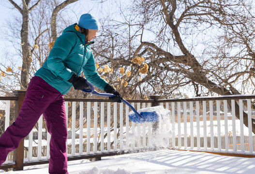 Woman in coat shovels snow after snowstorm 