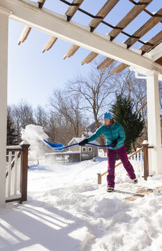 Woman bends shovel snow after snowstorm trellis