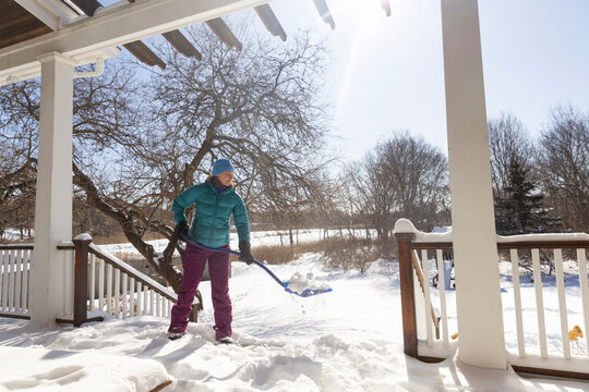 Woman shovels snow on deck  after snowstorm 