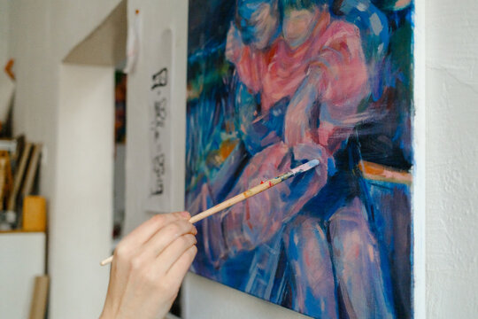 the artist's hands painting a picture