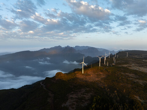 Aerial view of wind turbines at Bica da Cana on a mountain ridge with golden light and clouds in Ponta do Sol, Madeira, Portugal.