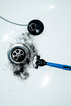 a shaving razor with foam and dark hair next to the drain