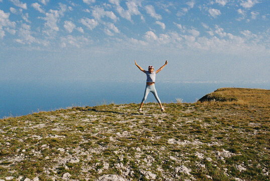 Happy smiling girl jumping at mountains at summer.