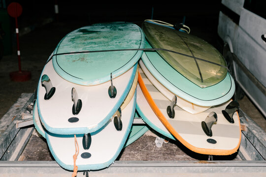 Surfboards arranged on a wooden rack against the dark background