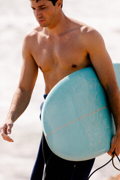 Surfer walking along a Moroccan beach after an intense surfing session