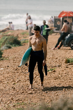 A surfer walking on a beach in Morocco after a session of surf