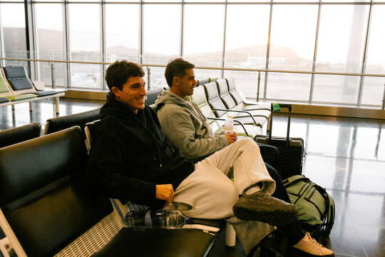 Friends sitting with their suitcases in the waiting area of an airport