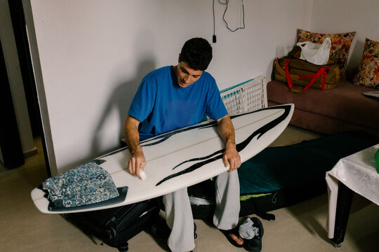 Surfer waxing his board getting ready to go on a surfing practice