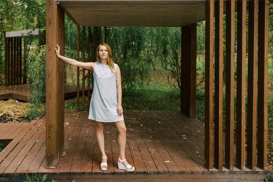 Woman Stands on Wooden Platform in Park During Daylight Hours
