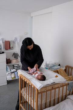 Older Woman Dressing Newborn Baby In Nursery At HomeOlder Woman 