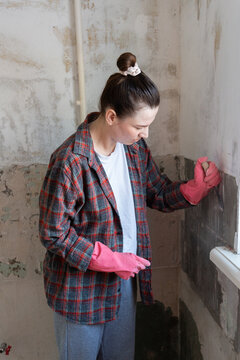 Woman Removing Old Tiles from Wall Indoors
