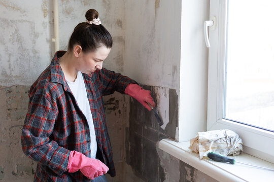 Woman Removing Old Tiles from Wall Indoors
